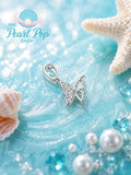 Sterling silver butterfly pendant with pearl on a beach background with starfish